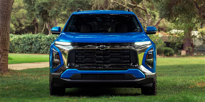 Blue Chevy Equinox parked on grass with trees in the background