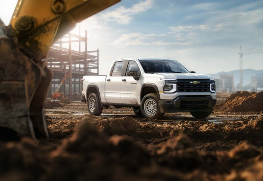 Silver Chevrolet Silverado on dirt road with construction site in background